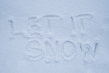 LET IT SNOW text handwritten in snowy winter season surface. Freezing cold weather. Climate change challenging conditions concept