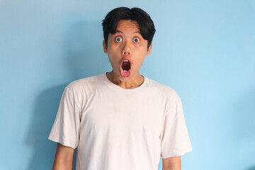 Shocked face of Asian young man in white t-shirt on a isolated background