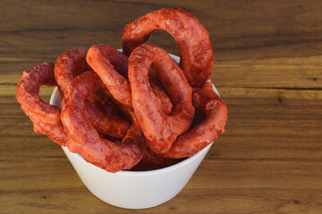 Fototapeta premium Close-up of crunchy Ecuadorian sweet rings in a white bowl on a wooden background, traditional Latin American snack.