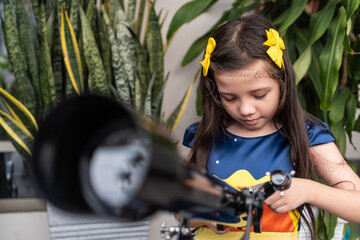 Latin girl closely examining a telescope outdoors