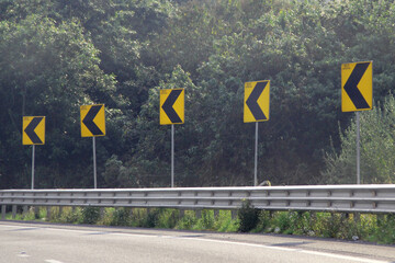 Arrow sign to the left of a curve on the road indicates the movement permitted to drivers traveling...