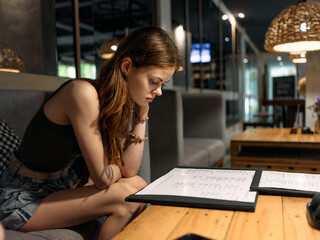 Young woman deciding what to order at a cafe while checking her phone