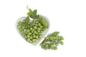 Fresh green peas in a heart-shaped bowl isolated on white background
