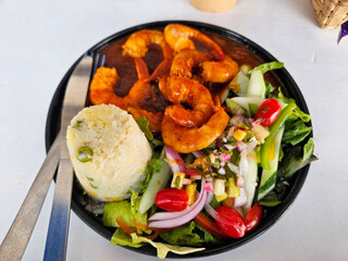Cenital View of A plate of shrimp and salad is placed on a table . The shrimp is cooked and served with a side of mashed potatoes. The salad is a mix of greens and vegetables