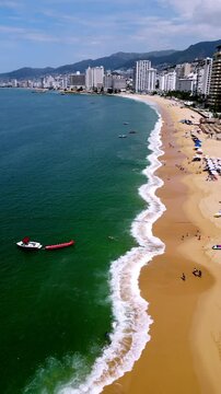 Vertical aerial video of the waves in Icacos Bay, capturing the rhythmic movement of the ocean along Acapulco's coastline