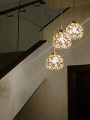 Ceiling with modern lights next to stylish staircase at night, low angle view.