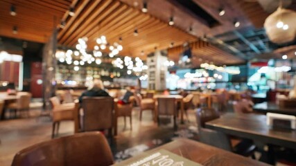 Blurred cozy stylish restaurant interior with warm ambient lighting empty tables. Soft bokeh effect highlights relaxed atmosphere perfect for social gatherings quiet moments. Food drink people