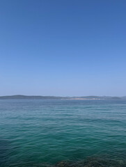 Fototapeta premium scenic view of island in the Adriatic Sea against clear blue sky on a sunny day in Dalmatia, Croatia with space for text 