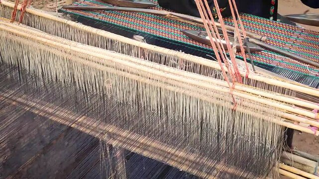 Khadi worker making clothing fabric with cotton and silk with village background