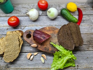 Dried meat on a cutting board surrounded by vegetables.