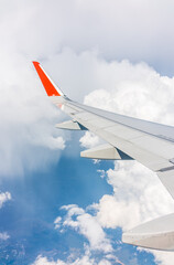 Fototapeta premium View from the airplane window at a beautiful cloudy sky and the airplane wing