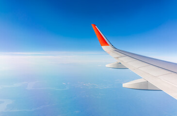 Fototapeta premium Aerial view from airplane window above green ground. View from the airplane window with beautiful clouds at sunrise
