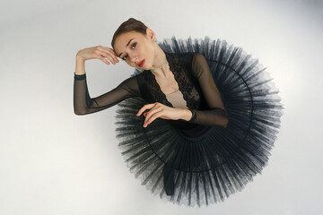 portrait of a young ballerina in a black tutu dancing with her hands moving top view, immersion in...
