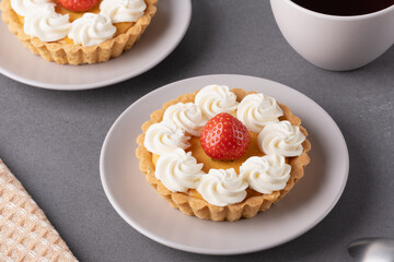 Freshly made strawberry tarts served with coffee on a grey table setting