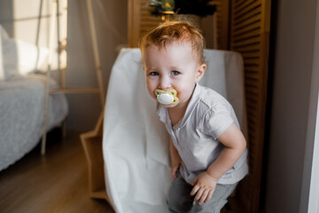 Little kid in messy room. toddler one year old baby girl with funny facial expression playing in...