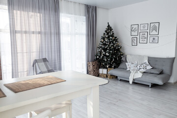 Light Scandinavian room interior with Christmas decorations. Selective focus. New Year's room interior with a fir tree and branches.