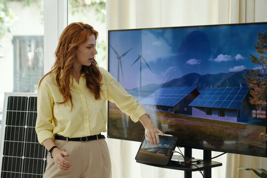 Young woman pointing at TV screen and presenting her report at presentation
