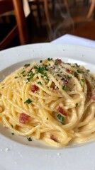 Delicious italian cuisine: closeup of steaming spaghetti carbonara with crispy bacon and fresh herbs