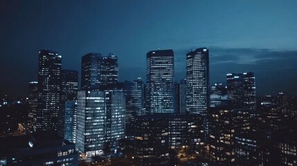 Fototapeta premium A view of a modern cityscape at night with tall skyscrapers illuminated by bright lights.