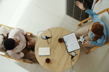 Top view of engineer giving interview about work of solar panel to journalist in office