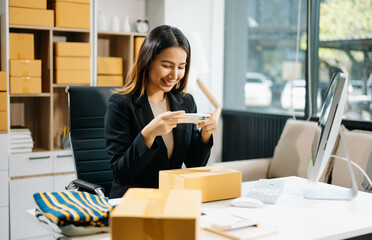 Young business owner woman prepare parcel box and standing check online orders for deliver to customer on tablet, laptop Shopping Online concept.
