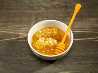 Honey with honeycomb and a honey dipper in a small bowl.