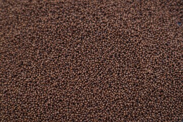 The background and texture of Betta ornamental fish pellets or food isolated on a pink background, with a close up view.