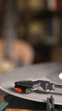 Vintage turntable close-up. Needle glides across the spinning silver record. One hand operates the pickup. 4k vertical video.