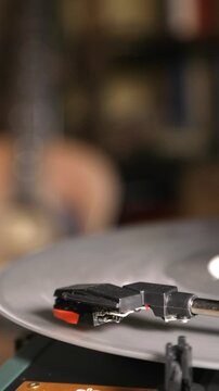 Vintage turntable close-up. Needle glides across the spinning silver record. One hand operates the pickup. 4k vertical video.