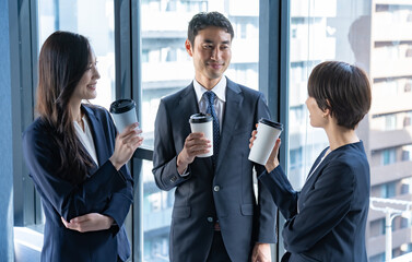 飲み物を持ち談笑をするスーツを着た男女