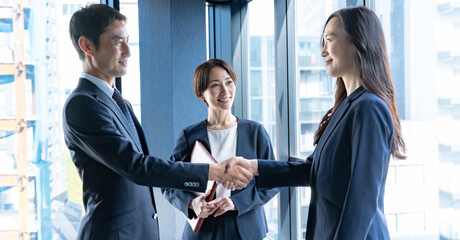 会議室で握手をするスーツを着た男女