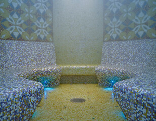Turkish bath or steam sauna with mosaic tiles inside male locker room of spa or wellness are...