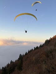 Parapente au dessus du Lac d' Annecy. Vol de parapente en montagne au dessus du brouillard. Sport extrême. Voler le soir au dessus de la brume avec un coucher de soleil.
