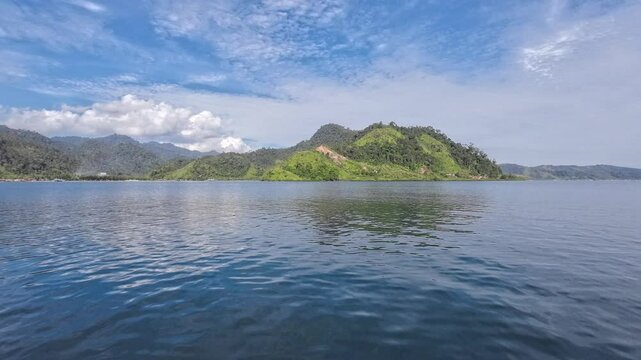 View of the hills from the sea. Blue cloudy sky. The footage taken moving sideways. Puncak Paku, Mandeh, West Sumatra, Indonesia