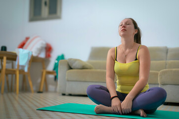 Obraz premium Young woman doing yoga exercises and meditating at home
