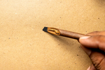 Human hand writing using calligraphy reeds on brown card