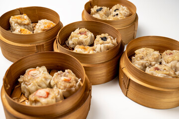 Assorted chinese dim sum dumpling on bamboo wooden basket bowl isolated over white background