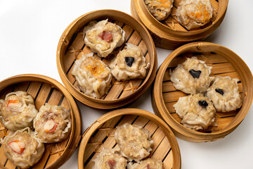 Assorted chinese dim sum dumpling on bamboo wooden basket bowl isolated over white background