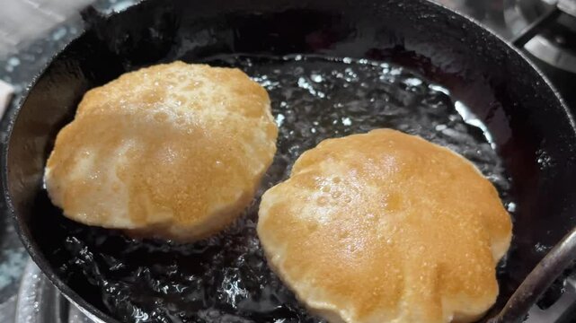 Closeup of homemade Puries or fried indian flat bread are being fired on the hot oil