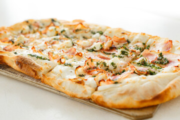 Pizza with bacon in Roman style served with fresh tomatoes on white table at cozy home