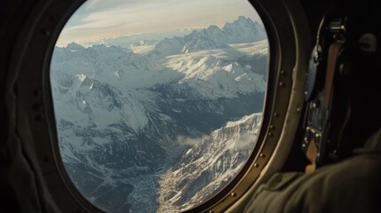 Naklejka premium Airplane window shot of snow-capped mountains and expansive wilderness below. 