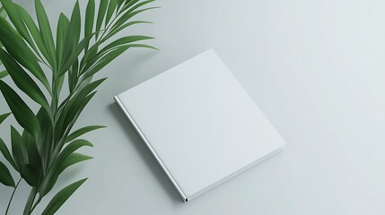 A minimalist scene featuring a blank book and a green plant, suggesting creativity and inspiration.