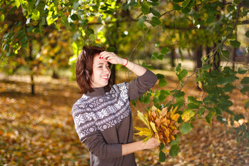 Woman is standing in a park with a basket of leaves in her hand