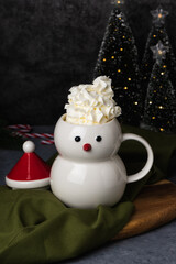 Christmas snowman mug with hot chocolate, whipped cream and marshmallows. Christmas Eve in a cozy home with a hot cocoa drink