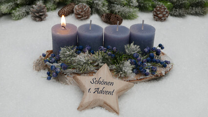 Dekoration zum ersten Advent: Adventskranz mit blauen Kerzen. Auf einem Stern steht der Text wir wünschen einen schönen 1. Advent.	