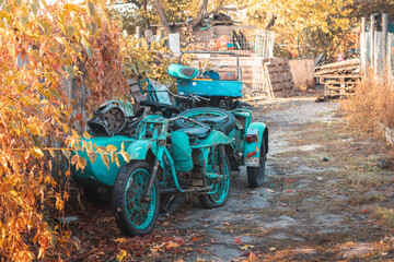 An old abandoned motorcycle with a sidecar in autumn village