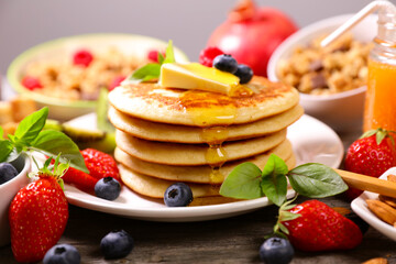 stack of american pancakes with berries, butter and syrup