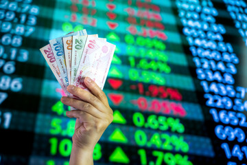 Turkish lira in woman hand and stock market screen, monetary graphic background              
