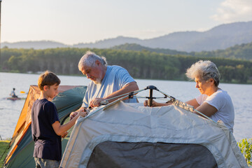 Family Setting Up a Tent Together Outdoors, Highlighting Camping, Bonding, and Generational Connection, Capturing the Joy of Spending Time in Nature, Teamwork, and Outdoor Adventure at Sunset