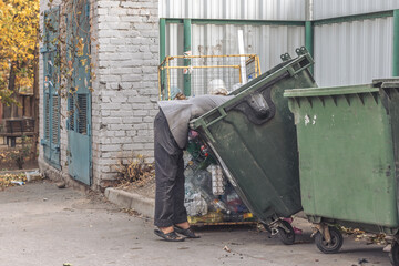 A homeless person leaned into a trash can in search of some food